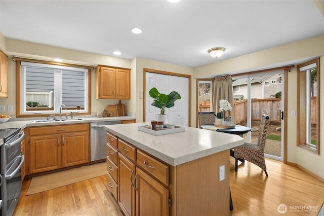 kitchen with a healthy amount of sunlight, appliances with stainless steel finishes, light wood-style floors, and a sink