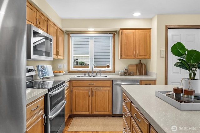 kitchen featuring a sink, stainless steel appliances, brown cabinetry, and light countertops