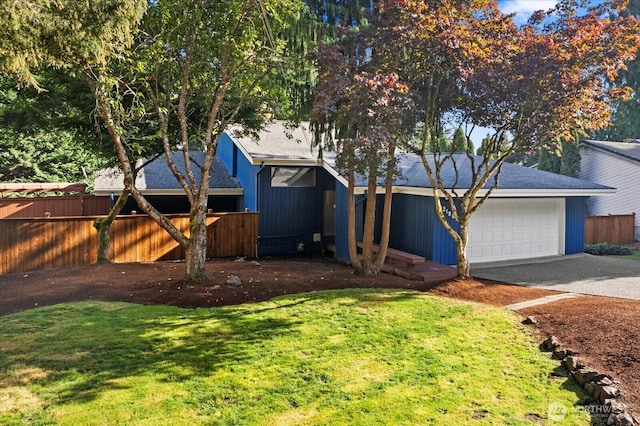 view of front of property with an attached garage, fence, aphalt driveway, and a front yard