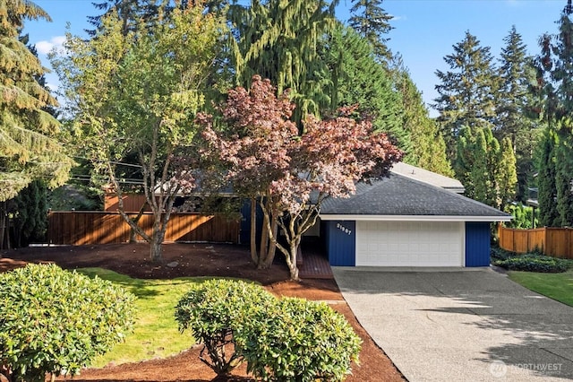 view of front of property featuring roof with shingles, fence, driveway, and an attached garage