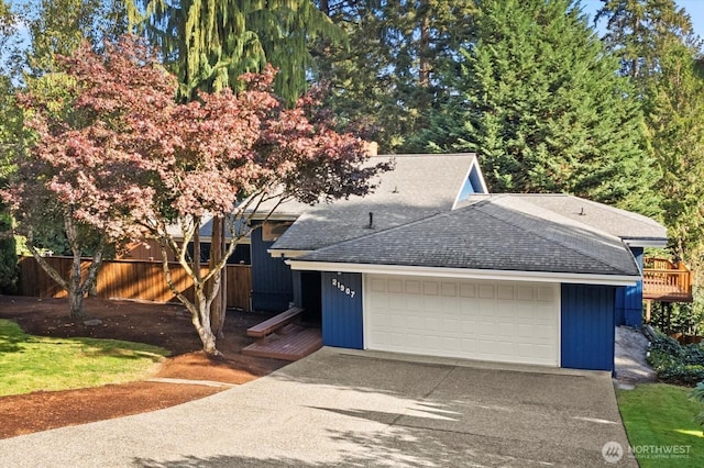 view of front of home with a garage, a shingled roof, and fence