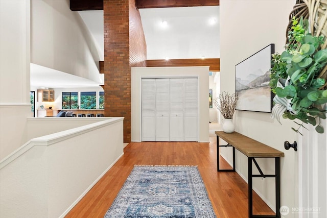 entrance foyer with a towering ceiling, wood finished floors, and beamed ceiling