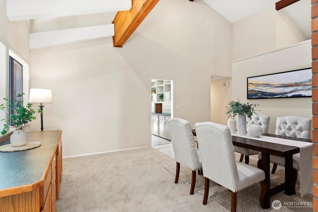 dining room with light carpet, baseboards, high vaulted ceiling, and beam ceiling