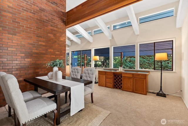 dining room with a healthy amount of sunlight, beamed ceiling, and light carpet