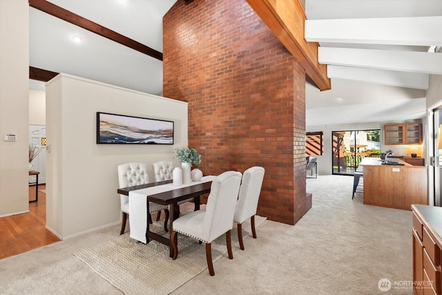 dining area with high vaulted ceiling, light carpet, brick wall, baseboards, and beamed ceiling