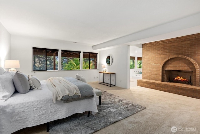 carpeted bedroom with connected bathroom and a fireplace