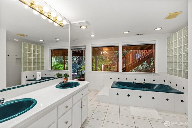 bathroom featuring a garden tub, visible vents, a sink, and tile patterned floors