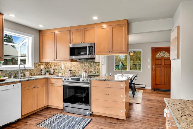 kitchen featuring light brown cabinets, a wealth of natural light, decorative backsplash, appliances with stainless steel finishes, and a sink