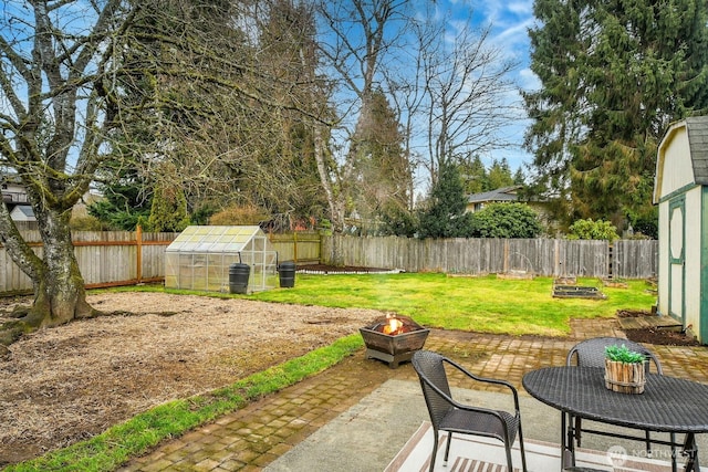 view of yard with a patio, a fenced backyard, an outdoor fire pit, an exterior structure, and an outdoor structure