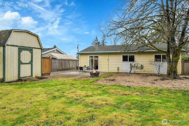 rear view of property with a patio, fence, an outdoor structure, a storage unit, and a lawn