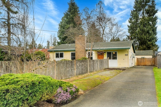 ranch-style home with a fenced front yard and a chimney