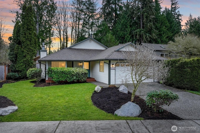 ranch-style house featuring a front yard, an attached garage, driveway, and a shingled roof