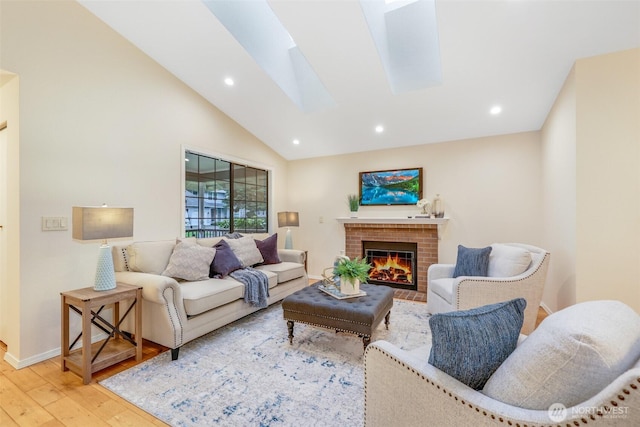 living area featuring wood finished floors, recessed lighting, a skylight, baseboards, and a brick fireplace