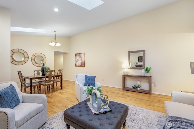 living room featuring recessed lighting, vaulted ceiling with skylight, an inviting chandelier, and wood finished floors