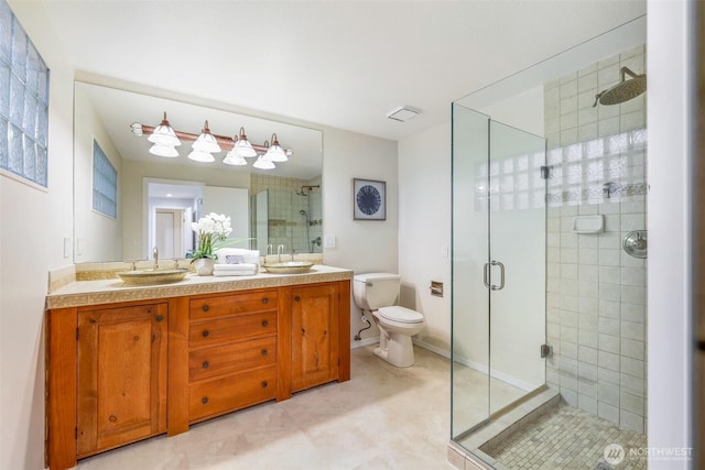 bathroom with double vanity, a stall shower, toilet, and a sink