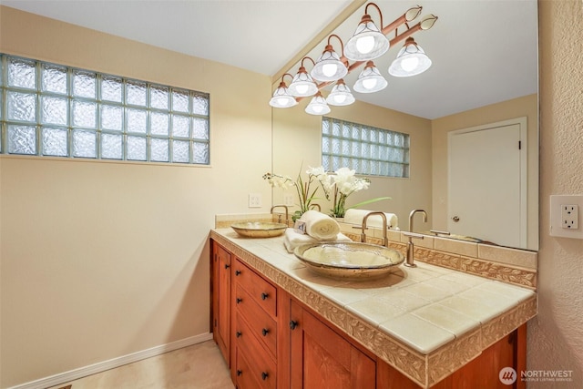 bathroom with a sink, baseboards, and double vanity