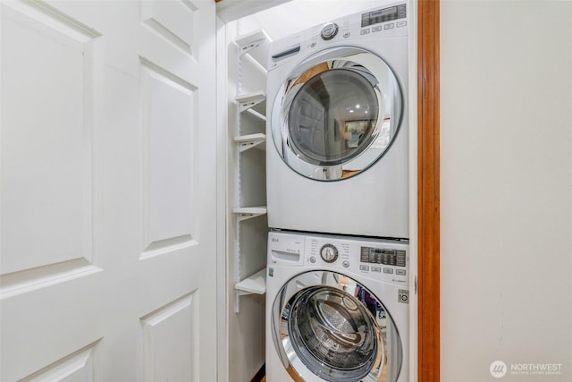 clothes washing area featuring stacked washer / dryer and laundry area