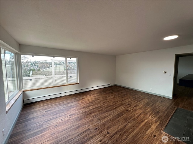 empty room with a baseboard heating unit, dark wood-style flooring, and baseboards