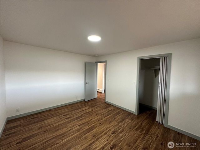 unfurnished bedroom featuring a closet, dark wood-style flooring, and baseboards