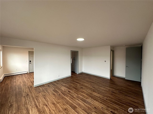 empty room with dark wood-style floors, a baseboard radiator, and baseboards