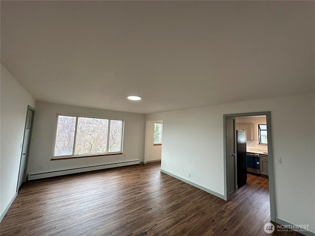 spare room featuring dark wood-style flooring, baseboards, and baseboard heating