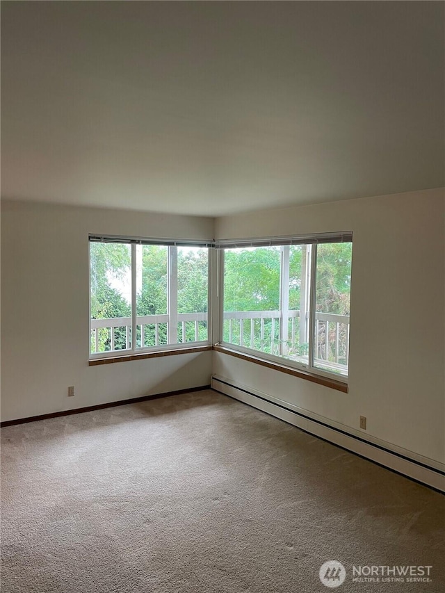 spare room with a baseboard heating unit and carpet