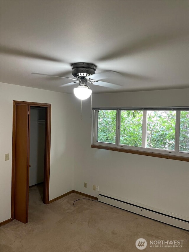 unfurnished bedroom featuring light carpet, multiple windows, baseboard heating, and baseboards