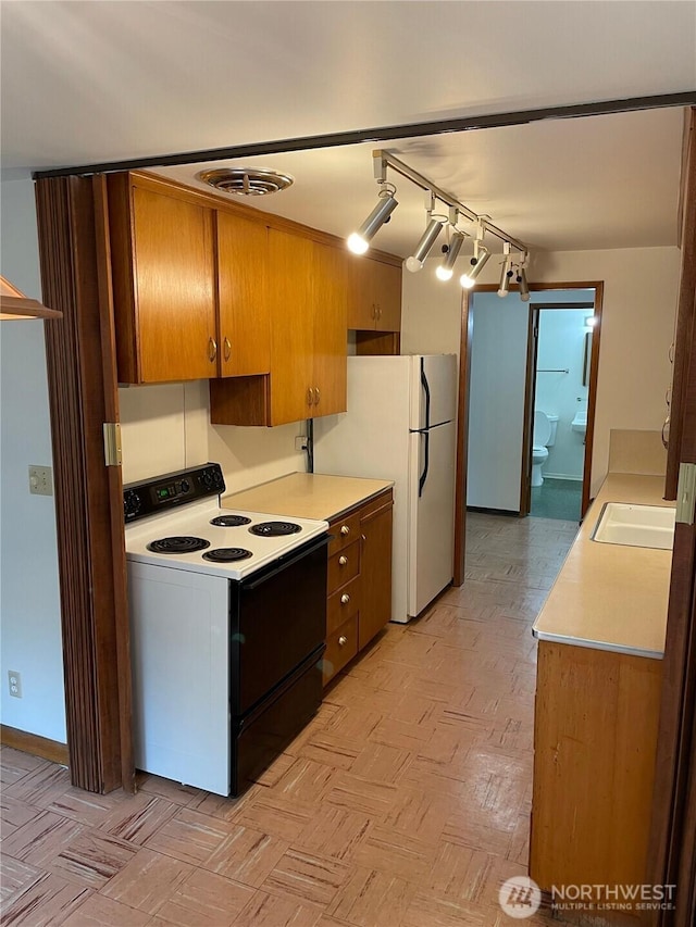 kitchen featuring light countertops, visible vents, freestanding refrigerator, a sink, and range with electric cooktop