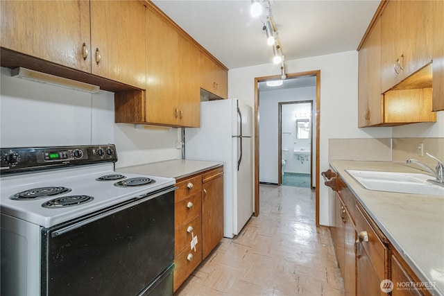 kitchen featuring electric stove, freestanding refrigerator, light countertops, light floors, and a sink