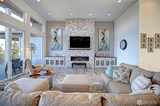 living room with recessed lighting, wood finished floors, and a large fireplace