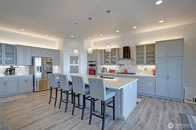 kitchen with a sink, appliances with stainless steel finishes, wall chimney exhaust hood, and gray cabinets