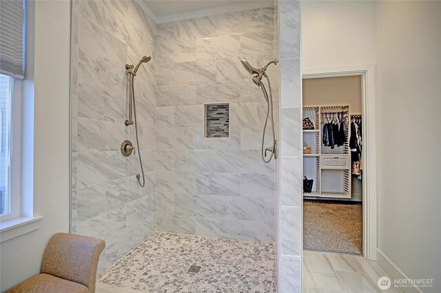 bathroom featuring a walk in closet and a tile shower