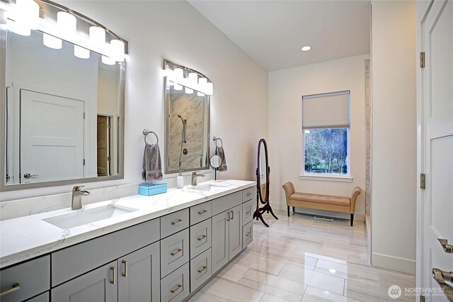 bathroom with double vanity, baseboards, and a sink