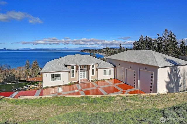 view of front of property featuring a front yard, an attached garage, a patio area, and a mountain view