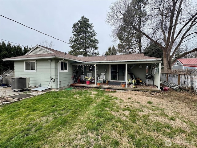 rear view of house with a lawn, cooling unit, and fence