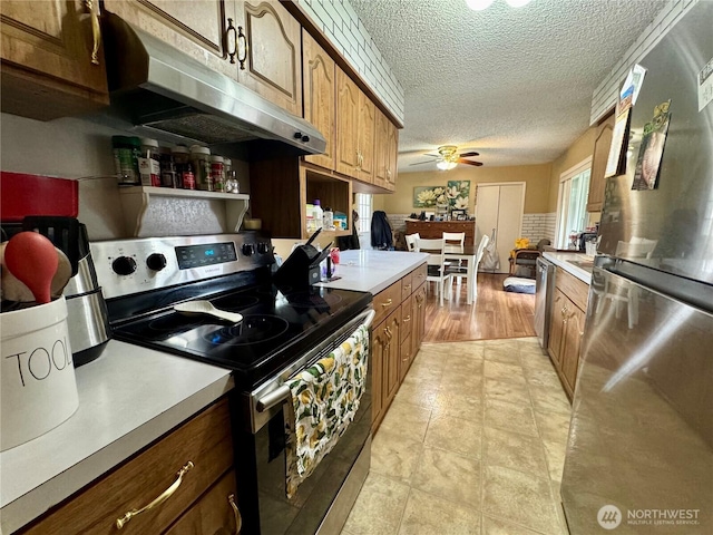 kitchen with a textured ceiling, light countertops, under cabinet range hood, and stainless steel appliances