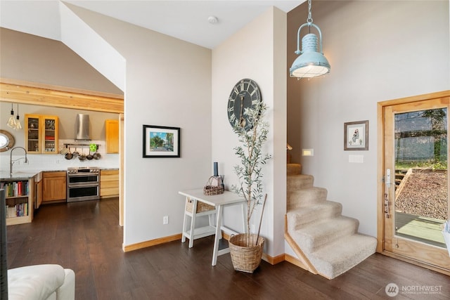 stairs with a towering ceiling, baseboards, and wood finished floors