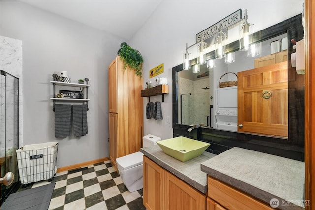 full bath featuring baseboards, stacked washer / dryer, tile patterned floors, vanity, and a shower stall