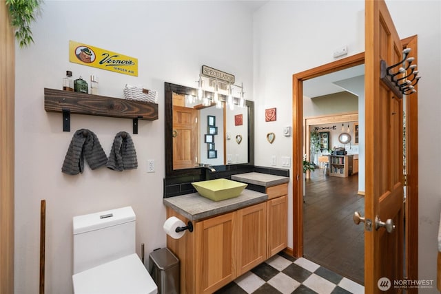 half bath with toilet, vanity, and tile patterned floors