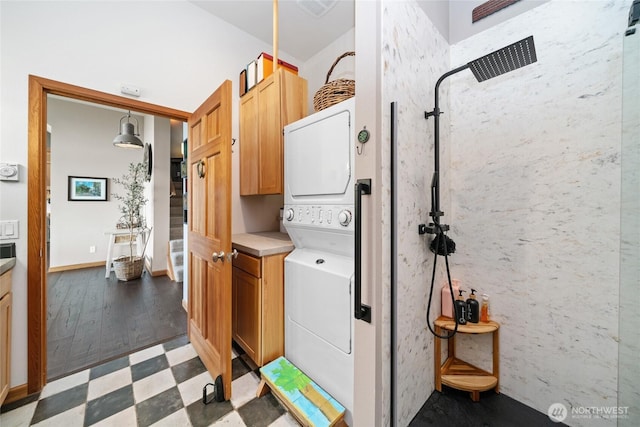 laundry area with visible vents, baseboards, stacked washing maching and dryer, cabinet space, and light floors