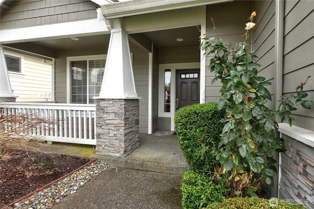 view of exterior entry with stone siding and a porch