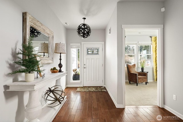 foyer entrance with dark wood-style floors, visible vents, and baseboards