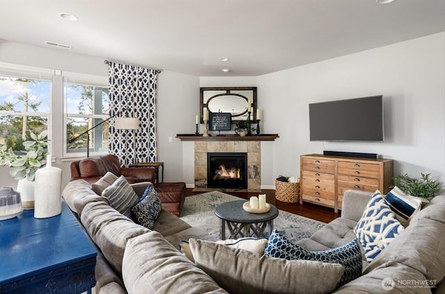 living area featuring visible vents, recessed lighting, a tile fireplace, and wood finished floors
