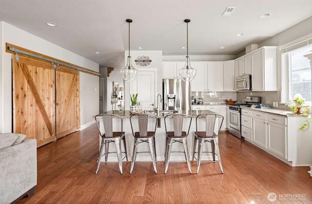 kitchen with decorative backsplash, light stone countertops, white cabinetry, and stainless steel appliances
