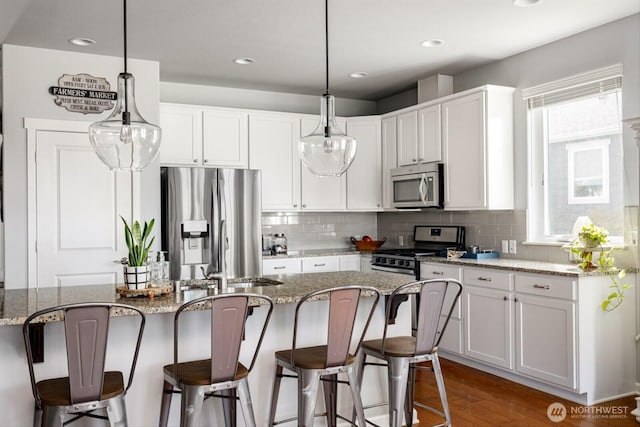 kitchen featuring stainless steel appliances, a breakfast bar, white cabinets, and decorative backsplash