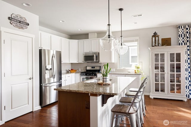 kitchen with visible vents, appliances with stainless steel finishes, a center island, and dark wood-style flooring