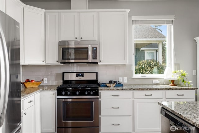 kitchen with light stone counters, backsplash, appliances with stainless steel finishes, and white cabinetry