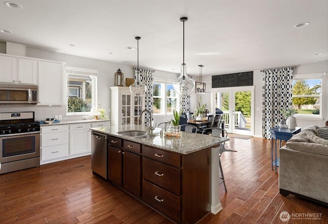 kitchen featuring a sink, dark wood-style floors, open floor plan, stainless steel appliances, and white cabinets