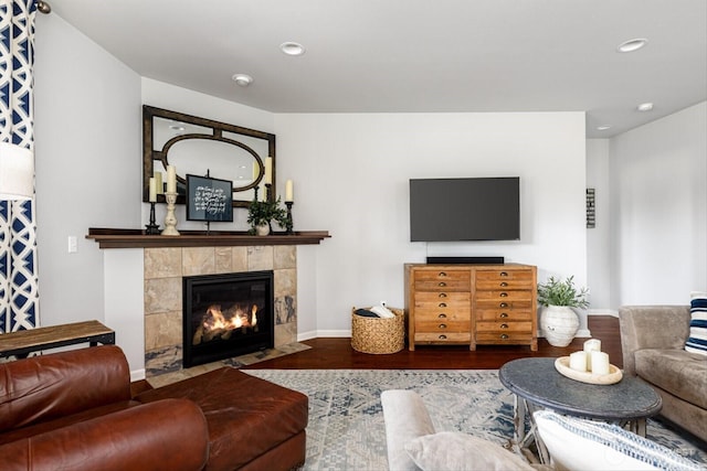 living room featuring a tiled fireplace, recessed lighting, wood finished floors, and baseboards