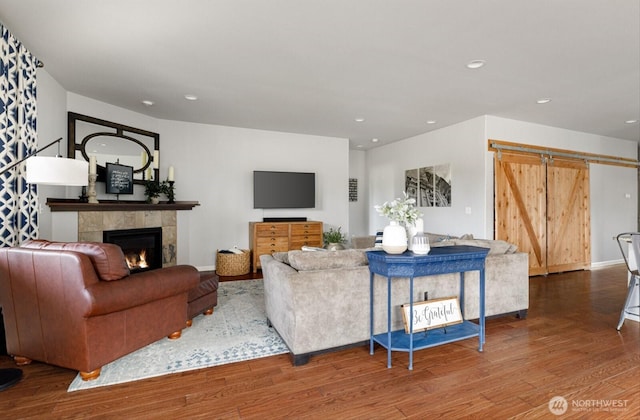living area featuring wood finished floors, recessed lighting, a barn door, a fireplace, and baseboards